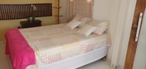 加利纽斯Pousada Monte Carlos的一张带粉色和白色棉被及枕头的床