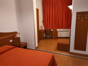 CastelgombertoAlloggio Al Ponte的一间卧室配有床、书桌和红色窗帘