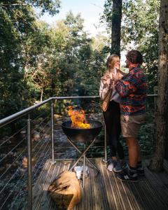 格伦科RiverBeds - Luxury Wee Lodges with Hot Tubs的两个人站在烧烤架旁边的甲板上
