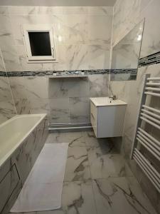 阿让特伊appartement luxueux 70m2, 2 chambres的带浴缸、水槽和镜子的浴室