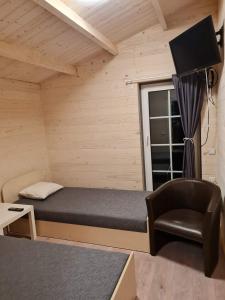 Sodybos Narūnas namelis po egle的小房间设有一张床和一把椅子
