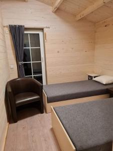 Sodybos Narūnas namelis po egle的小房间设有两张床和椅子