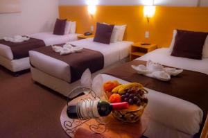 普诺Casona Plaza Balsa Inn的酒店客房设有两张床,桌子上放着一碗水果