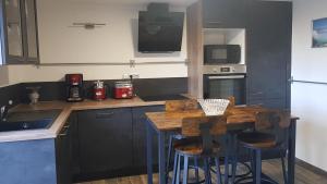 圣纳泽尔Suite Deluxe, calme proche Airbus et Chantiers de l'Atlantique的厨房配有木桌和2个吧台凳