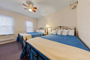 普莱西德湖普莱西德湖村派恩斯旅馆的一间卧室配有两张床和吊扇