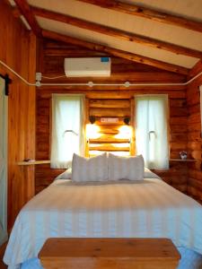 圣安东尼奥德阿雷科Cabaña Rural El Encuentro的一间卧室配有一张带白色床单的床和两个窗户。