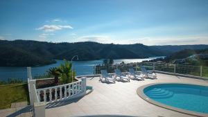 费雷拉杜泽济里Lago Azul Villas的游泳池配有椅子,享有河景