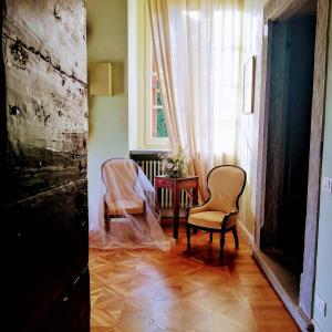 贝加莫B&B Dimora Delle Donnole Bergamo Alta的一间设有两把椅子、一张桌子和一个窗户的房间