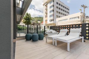 弗洛里亚诺波利斯ZEE Studios a 200m da beira-mar norte的阳台配有白色椅子,享有建筑的景致。