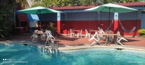 伊基托斯Poseidon Guest House的一个带桌椅和遮阳伞的游泳池