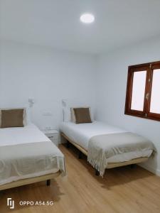 克鲁兹·德·特赫达Texeda Room Suites的配有白色墙壁和木地板的客房内的两张床