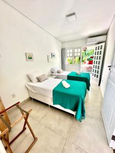 阿拉亚尔达茹达Vista para o mar Arraial d'Ajuda的一间卧室配有两张带绿床单和椅子的床