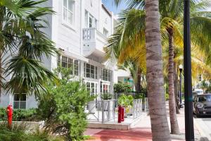 迈阿密海滩The Julia Hotel的一座白色的建筑,有棕榈树和一个红色的消防栓