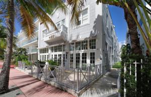 迈阿密海滩The Julia Hotel的一座白色的建筑,前面有棕榈树