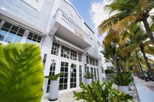 迈阿密海滩The Julia Hotel的一座白色的建筑,前面有棕榈树