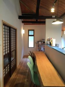 AyabeSatoyama Guest House Couture - Vacation STAY 43859v的一间带木桌和绿色椅子的用餐室