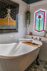 沃洛比Wollombi Wines的带浴缸的浴室,浴室设有彩色玻璃窗