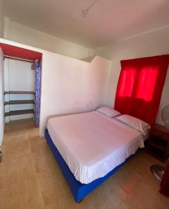 洛佩斯港海蒂旅馆的卧室配有白色的床和红色窗帘