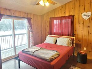 GilmourMarshmallow home的一间卧室配有一张带红色棉被的床和窗户。