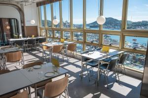 丽水市Hotel Kenny Yeosu的餐厅设有桌椅和大窗户。