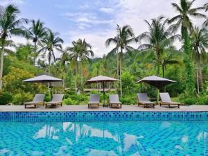 库德岛丛林沽岛度假村 的度假村的游泳池,配有椅子和遮阳伞