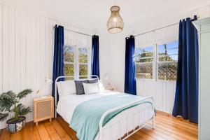 土乌巴Cheerful, Cosy Cottage - Near Rose Garden!的一间卧室配有一张蓝色窗帘的床