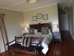 格拉罕镇The Ranch House at African Safari Lodge的一间卧室配有一张床和一个带枕头的长凳