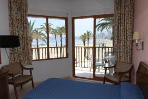 贝尼多姆科隆酒店的一间卧室配有一张床,享有海滩美景