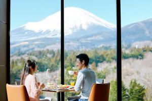 OyamaFuji Speedway Hotel - The Unbound Collection by Hyatt的坐在桌子上,享有山景的男人和女人