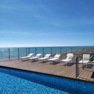 利多迪耶索罗大西洋酒店的一个带椅子的游泳池,背景是大海