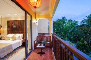 会安Ahoy Hoi An Boutique Resort & Spa的一间卧室设有一张床和一个阳台