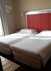 米兰苏萨酒店的配有红色床头板的酒店客房内的两张床