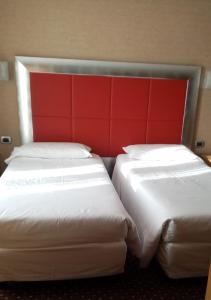 米兰苏萨酒店的配有红色床头板的酒店客房内的两张床