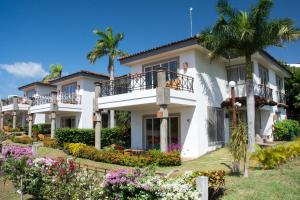 南圣胡安巴伊亚太阳海岸别墅公寓酒店的一座种植了棕榈树和鲜花的大型白色房屋