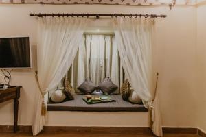 SodaoriGir Lion Safari Camp by Trulyy, Sasan Gir的配有窗帘的窗户的客房内的一张床位