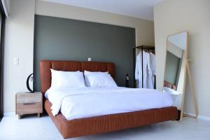 PaianíaSpacious & Minimal Apartment Near Airport Peania Coniann Filoxenia的一间卧室配有一张带白色床单和镜子的大床