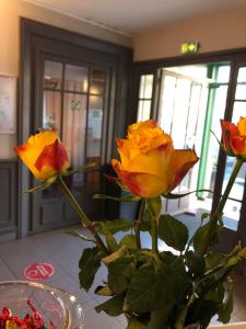 波城Hotel De Gramont的一张桌子上满是黄色和红色玫瑰的花瓶
