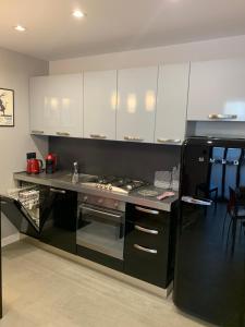 都灵CasaBella Inalpi Arena的厨房配有白色橱柜和黑色冰箱。