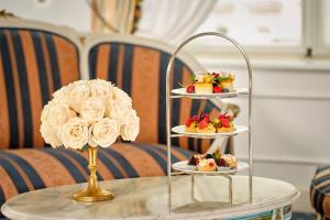 维也纳Hotel Imperial, a Luxury Collection Hotel, Vienna的桌子上摆着三层甜点,桌上放着一朵花