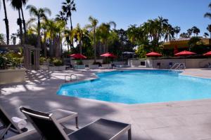 长滩长滩万豪酒店的度假村的游泳池配有椅子和遮阳伞