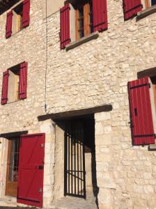 萨路特德沃克吕兹LA MAISON D’ALICE的一座石头建筑,设有红色的门窗