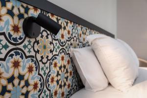 拉罗谢尔圣尼可拉酒店的一张带两个枕头的床铺,靠墙