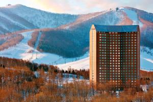留寿都村留寿都威斯汀度假酒店的山前的一座建筑,有滑雪场
