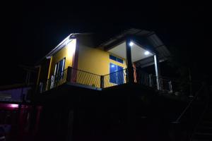 SibsāgarHira Panidihing Homestay的黄色房子,晚上带阳台
