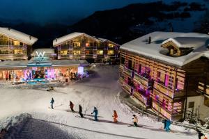 韦尔比耶韦尔比耶W酒店的一群人滑雪在建筑物前的雪地里