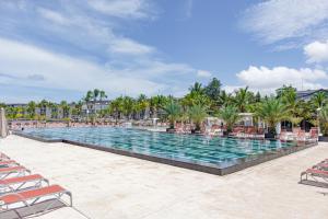 达喀尔泰鲁碧酒店的一个带椅子和棕榈树的度假村游泳池