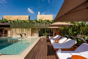 麦德林Elcielo Hotel & Restaurant的一座带椅子和遮阳伞的游泳池位于一座建筑旁边