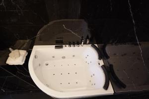 阿韦利诺Grand hotel irpinia & Family SPA的黑色瓷砖客房内的白色浴缸