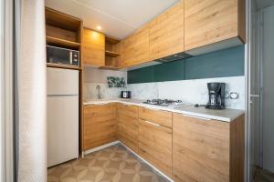 圣让-德蒙Camping Les Genêts的厨房配有木制橱柜和白色冰箱。