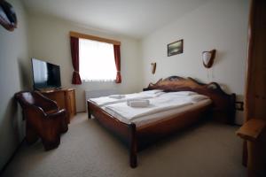 瓦茨Camelot Club Hotel的一间卧室配有一张床、一把椅子和电视